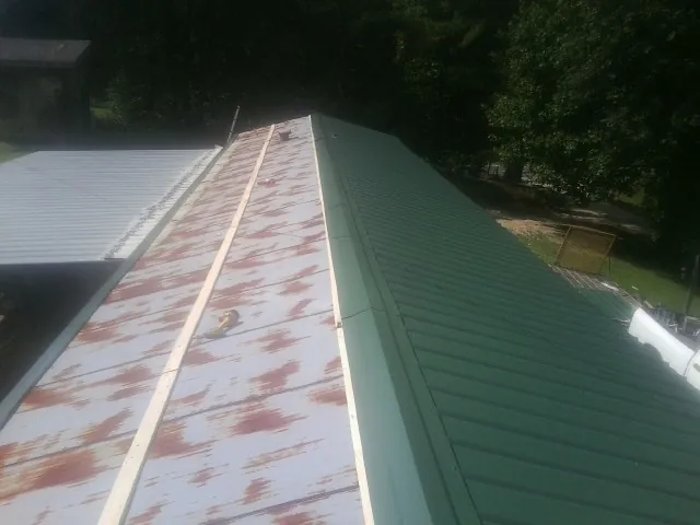 Old rusted panels beside newly installed green metal roofing — Wind Damage Roof Repair by Roofing Brothers in Westphalia