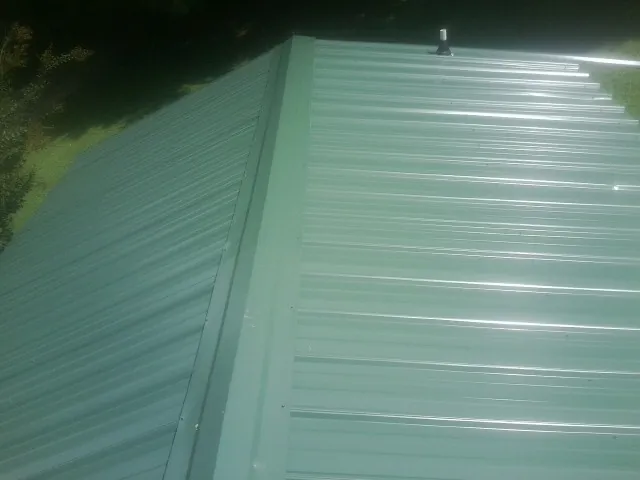 New green metal panels meeting at the ridge of a roof — Flat Roof Repair work by our crew in Westphalia